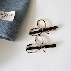 Detail view of acetate bow hair clips with tortoiseshell and marble patterns on white desk