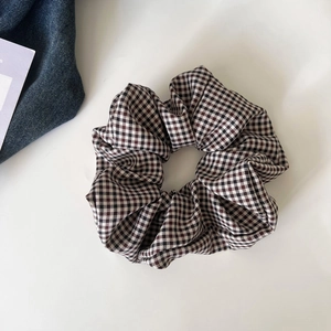 Macro detail of brown and beige houndstooth pattern fabric scrunchie with soft pleats