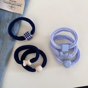 Close-up of high-elasticity hair ties with resin bow and checkerboard charms on denim fabric