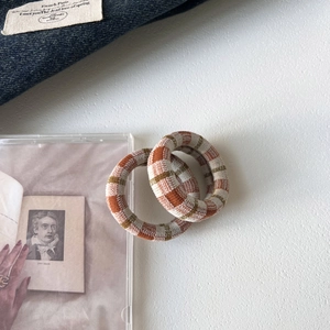 Detail of plaid seamless knit hair ties in brown and green on a vintage background