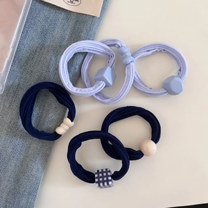 Close-up of six elastic hair ties with purple and navy beads and checkered patterns