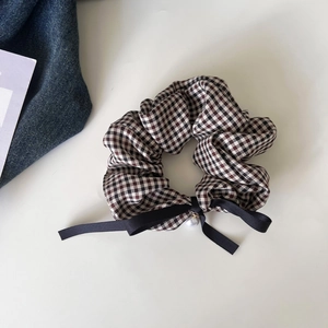 Close-up of houndstooth hair scrunchie with silk bow and faux pearl pendant detail