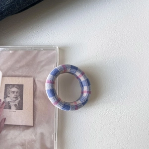 Detail of soft knitted plaid hair tie in blue and pink on minimalist white surface