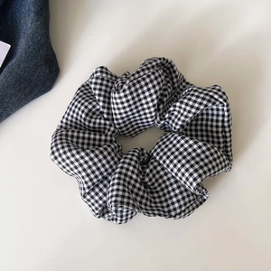 Classic black and white houndstooth checkered hair scrunchie with pleated fabric texture