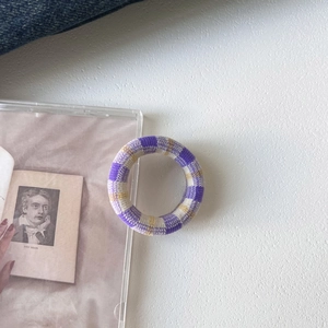Close-up of seamless purple and yellow checkered knit hair tie on textured background