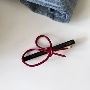 Detail of a handmade French acetate hair clip with a red bow and gold metal fastening