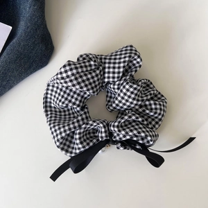 Detail of checkered houndstooth scrunchie with a black bow and pearl pendant charm