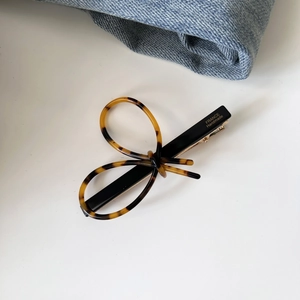Detail of acetate tortoiseshell bow hair clip with gold France Handmade logo on black base