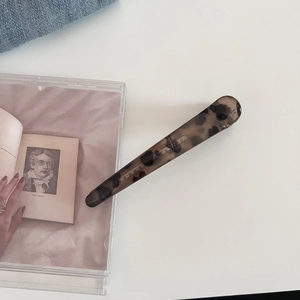 Dettaglio di un fermaglio per capelli vintage leopardato su uno sfondo minimalista