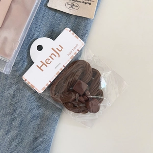 Close-up of three brown elastic hair bands with plastic buckles on blue denim fabric