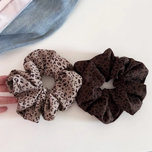 Detail showing two leopard print scrunchies in light khaki and dark brown soft fabric