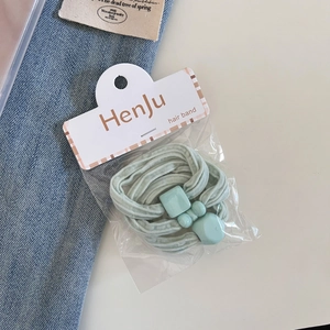Detailed macro view of a mint green elastic hair band with resin beads on denim background