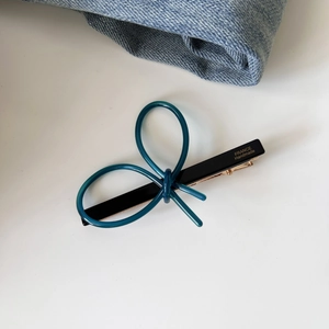 Detail of blue acetate bow hair clip with gold France Handmade lettering on black base