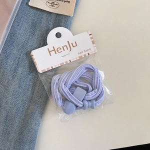 Detail of light purple elastic hair bands in transparent packaging on denim background