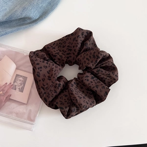 Close-up of leopard print hair scrunchie made of soft chiffon fabric on a white surface