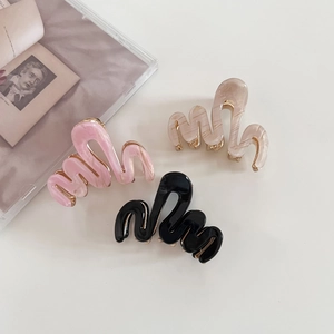 Trois pinces à cheveux ondulées en acétate rose, beige marbré et noir avec bordure dorée