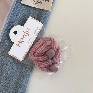 Close-up of elastic pink hair ties with matte heart and square beads on packaging