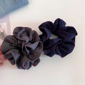 Detailed view of grey and navy heart print scrunchies with red stitched edges