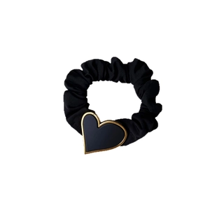 Chouchou élégant noir mat avec un pendentif cœur bordé d'or sur un fond blanc propre