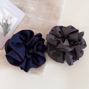 Detailed view of grey and blue scrunchies with red heart patterns and stitched edges