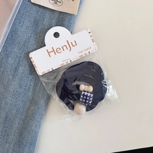 Close-up of sweet navy blue hair ties with cream beads and plaid detail on display card