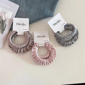 Chouchous en satin couleurs champagne rose et gris sur emballage de marque
