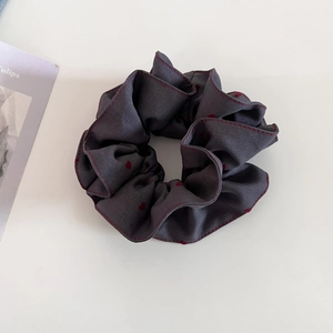Detail of grey scrunchie with red heart patterns and stitched edges on white background