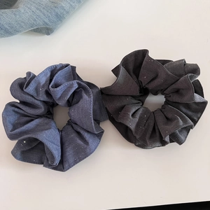 Gros plan sur des chouchous bleus et gris pailletés avec texture denim et reflets