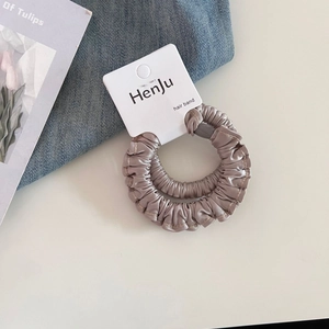 Gros plan de chouchous en satin de qualité en champagne et rose lotus sur carte de vente