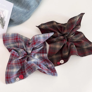 Detail of red and blue plaid scrunchie with button accents and soft textured fabric