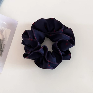 Detail of navy blue scrunchie with red hearts and contrast stitching on white background