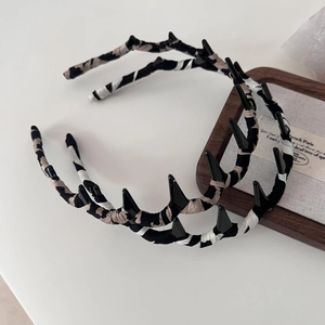 Detailansicht zweier Haarbänder mit Leopardenmuster, schwarzen Spikes und Stofftextur
