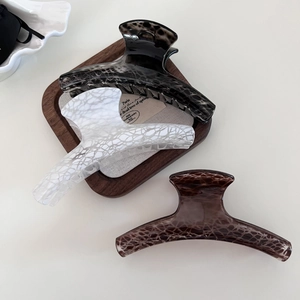 Detailed view of three large hair claws with a crackle pattern in grey, white, and brown