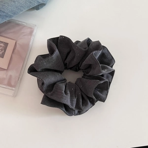Vue détaillée du chouchou en tissu gris foncé avec des paillettes argentées et plis