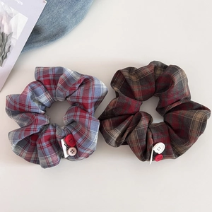 Detail of red and blue plaid scrunchies with vintage buttons on a soft background