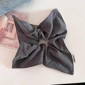 Vue détaillée du chouchou nœud papillon gris foncé scintillant sur une surface blanche