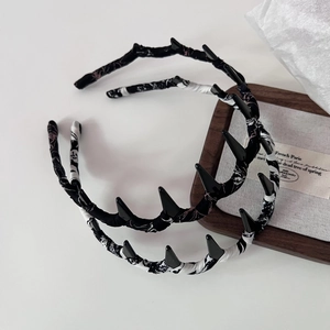 Detailansicht von Haarreifen im Punk-Stil mit Stoffstruktur auf einem Holztablett