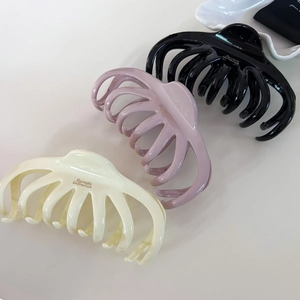 French claw clips in black, pink, and cream white displayed on elegant ceramic plate