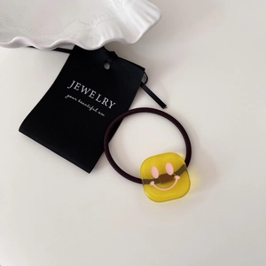 Close-up of yellow transparent square smiley face hair tie with high elastic band