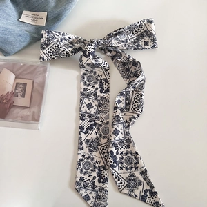Dettaglio di una sciarpa sottile in seta blu navy con motivo paisley a fiocco