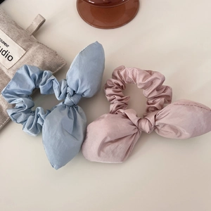 Détail de chouchous en texture soie rose et bleue avec nœuds d'oreilles de lapin