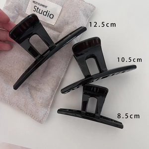 Trois tailles de pinces à cheveux noires brillantes élégantes sur fond blanc minimaliste