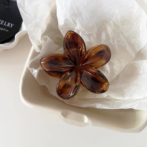 Detailed close-up of a vintage amber floral hair claw clip on a ceramic display tray