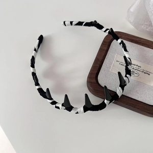 Detail eines gestreiften Haarreifens mit Punk-Spikes auf Vintage-Holztablett