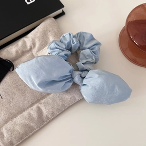 Chouchou minimaliste bleu clair avec nœud papillon et texture soyeuse sur sac en lin