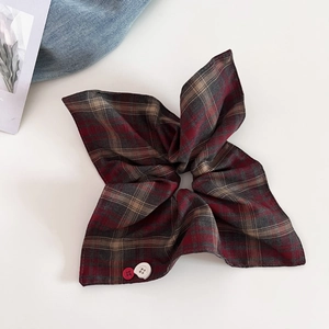 Detail of red and brown plaid scrunchie with cute buttons and vintage style cotton texture