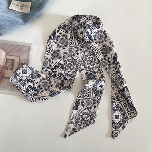 Dettaglio twilly blu navy con motivo paisley su sfondo vintage dallo stile minimalista