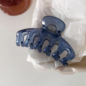 Detail view of a large translucent deep blue hair claw clip on soft textured white paper