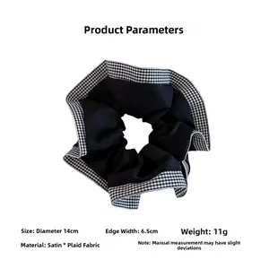 Detailed view of large black satin scrunchie with checkerboard trim and 14cm diameter size