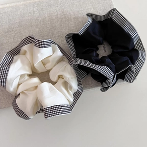 Detail of cream and black satin hair scrunchies with elegant houndstooth check patterns